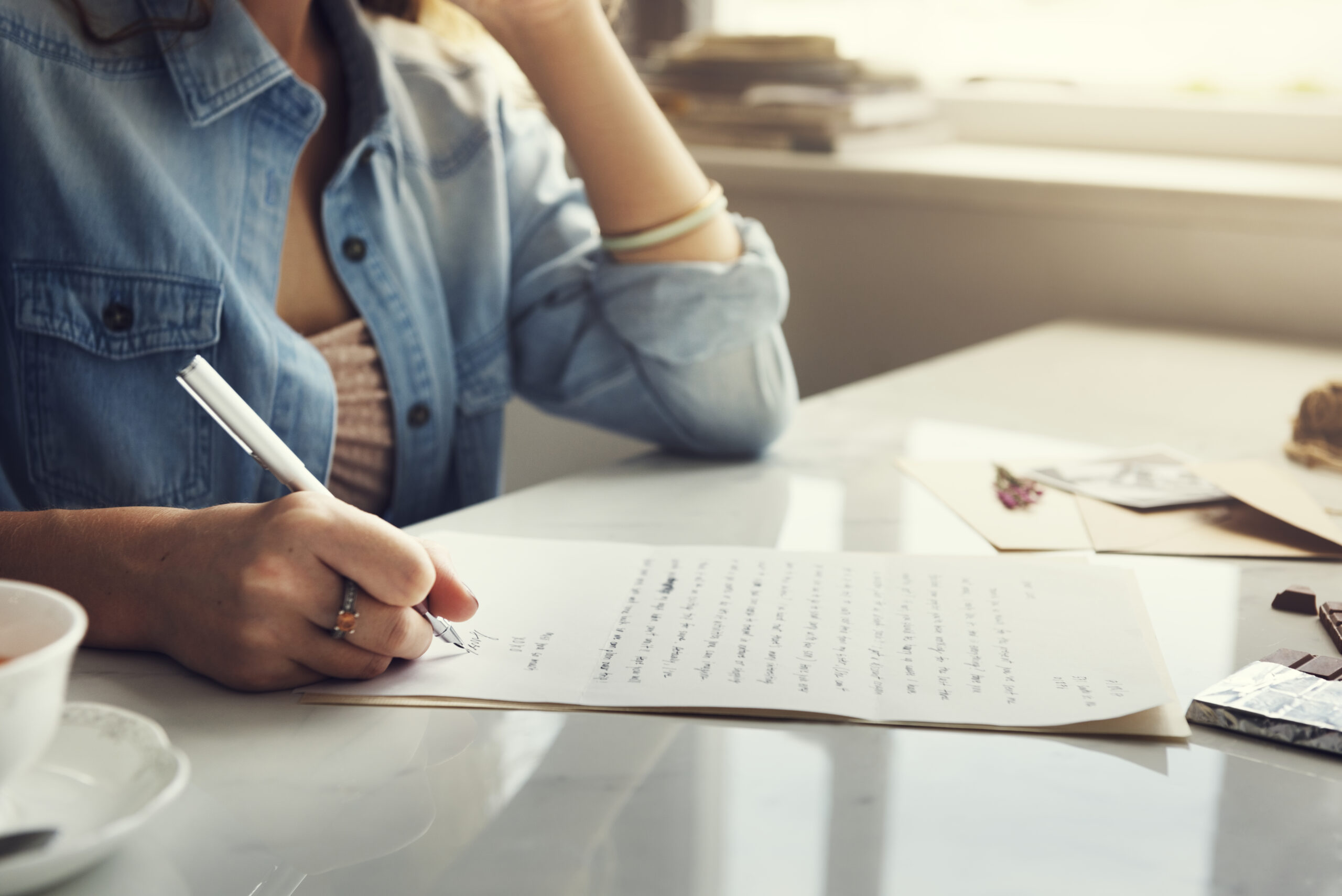 A woman writing a formal letter at a desk, representing the structured and precise Academic Writing Style of the UK.