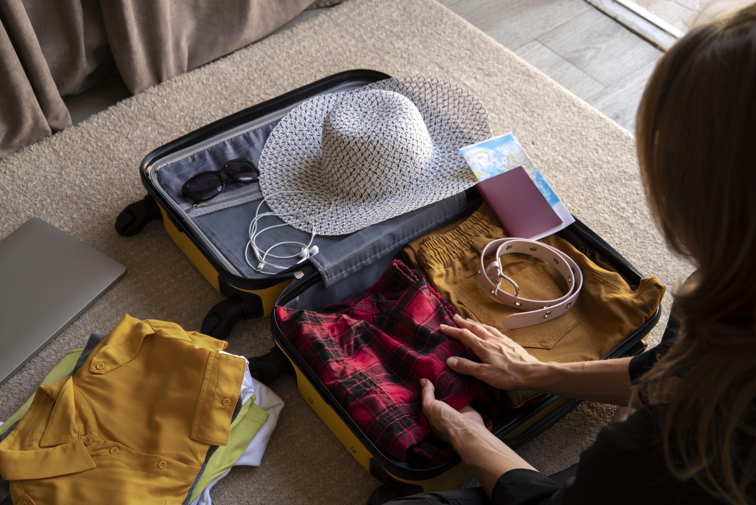 A traveler packing for Australia, organizing clothes, accessories, and travel essentials in a suitcase, including a sun hat, passport, and map.