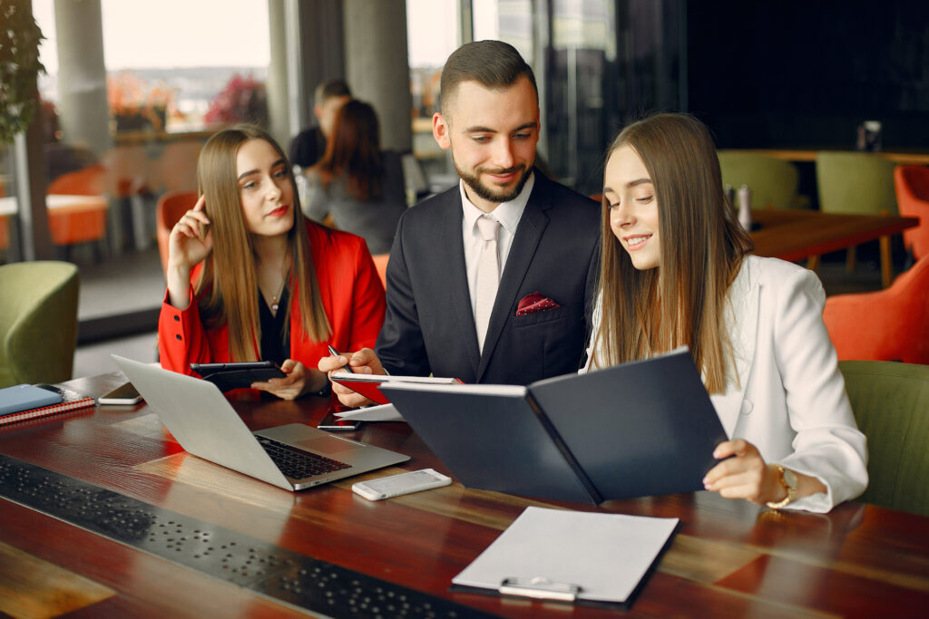 Business team collaborating on project, reviewing documents and using laptops.