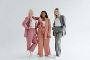 Three diverse women in stylish suits pose confidently.
