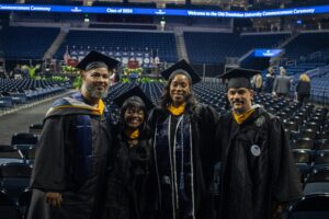 Four smiling Old Dominion University graduates in caps and gowns at their commencement ceremony.