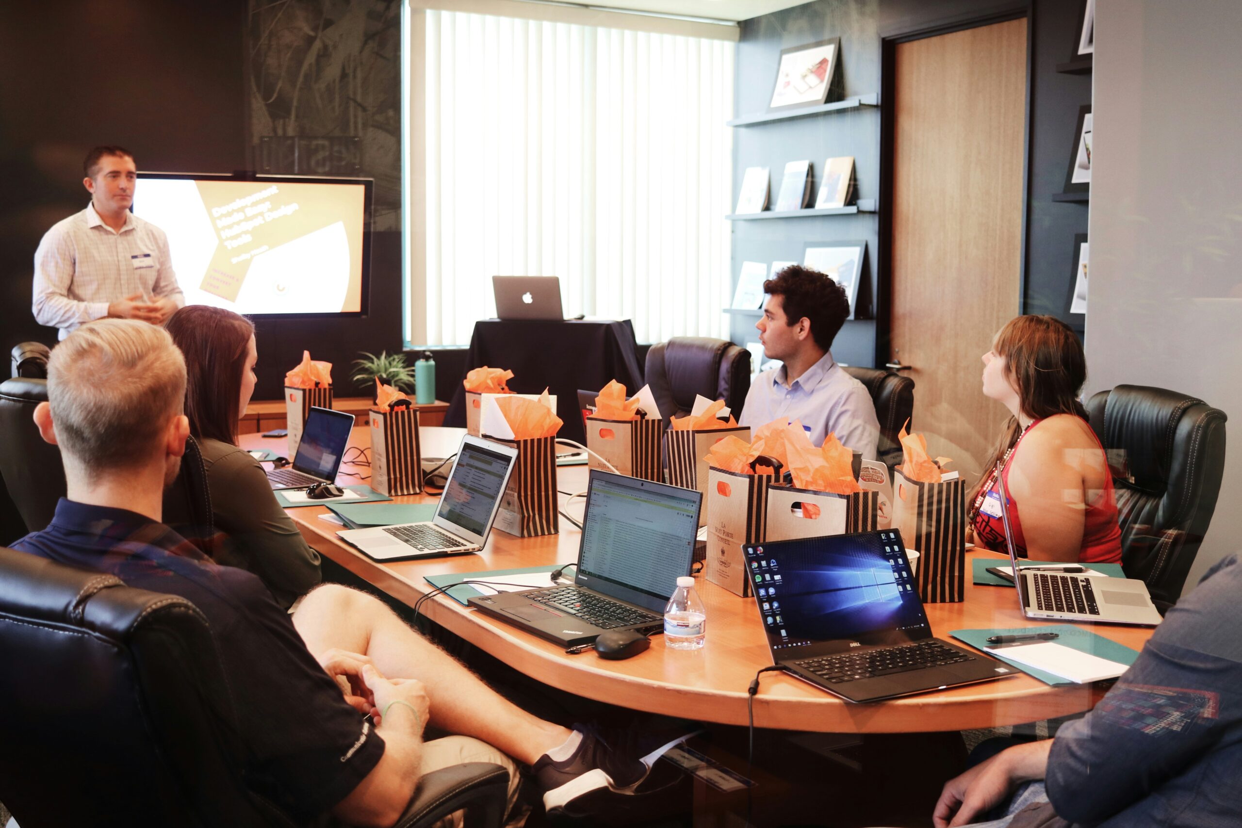 Students attending a digital marketing classroom session, listening to a presentation on digital marketing strategies while using laptops in a university seminar room.