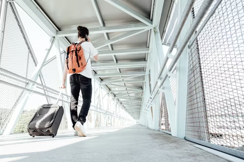 Man with backpack and suitcase walking on a walkway