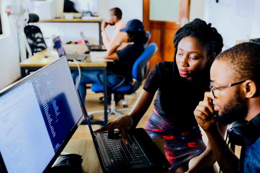 Young developers collaborating on coding projects in a modern workspace, representing innovation, teamwork, and technology-driven learning.