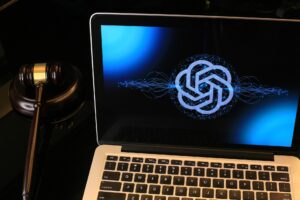 Laptop displaying the ChatGPT logo beside a judge’s gavel, symbolizing the debate over artificial intelligence, academic integrity, and its impact on college essay writing and admissions decisions.