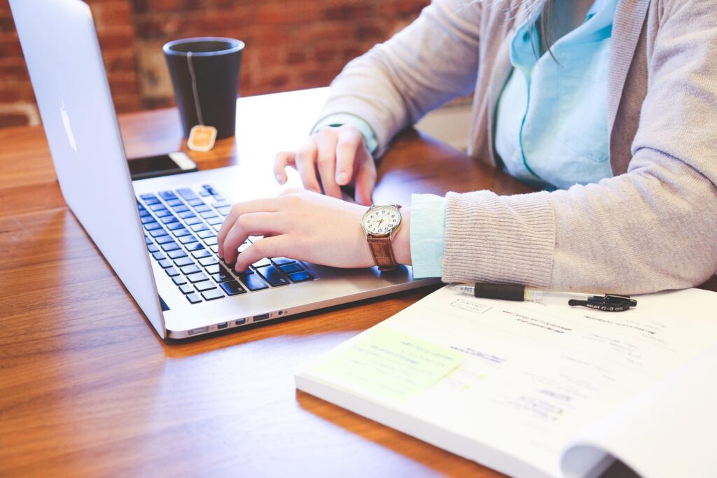 Finance and accounting student working on a laptop with study materials and notes, representing academic preparation for career opportunities in Europe's leading financial cities.