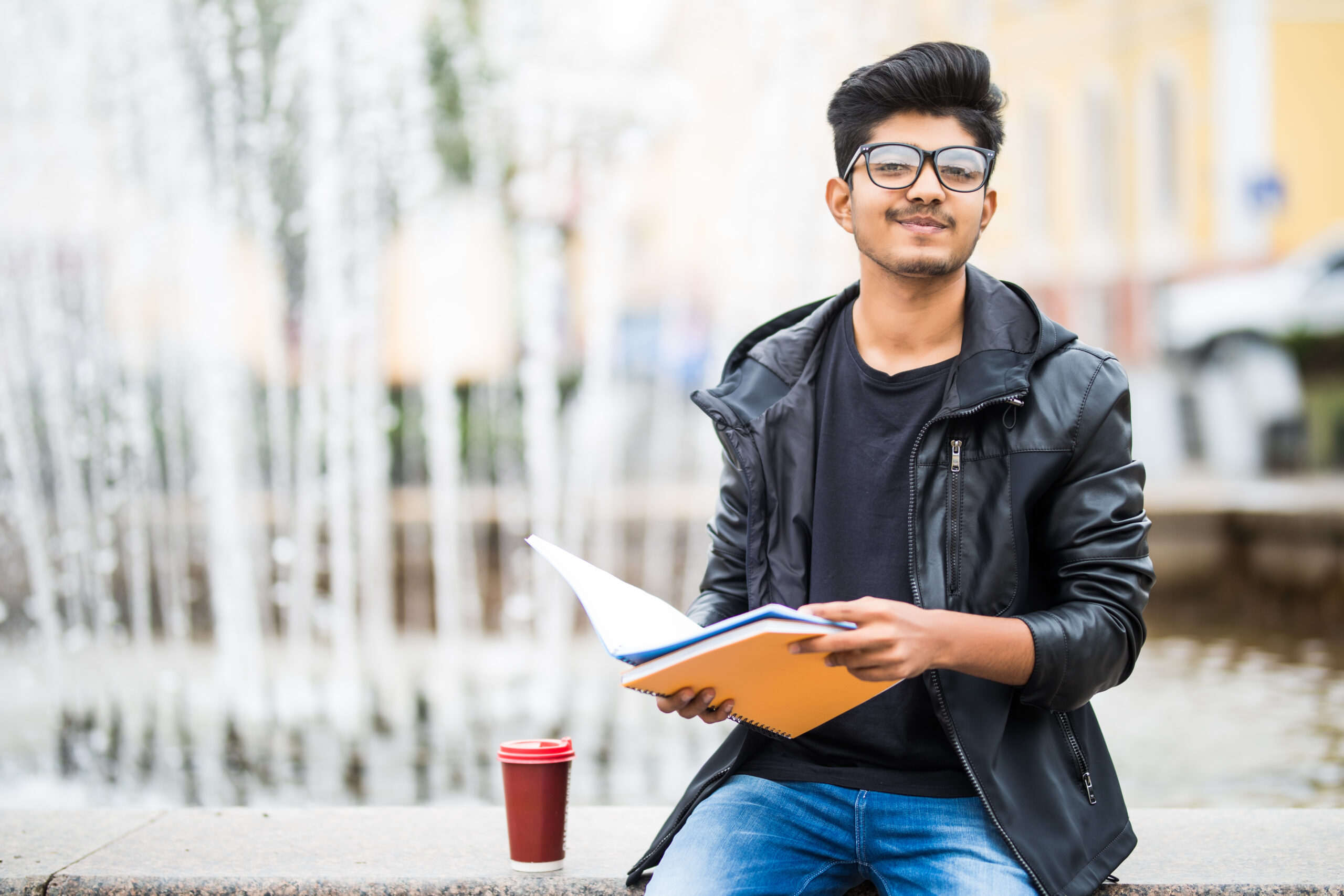 Medical student holding study materials while sitting on a university campus, representing graduates preparing to transfer their medical qualifications back to Southeast Asia after completing an international medical degree.