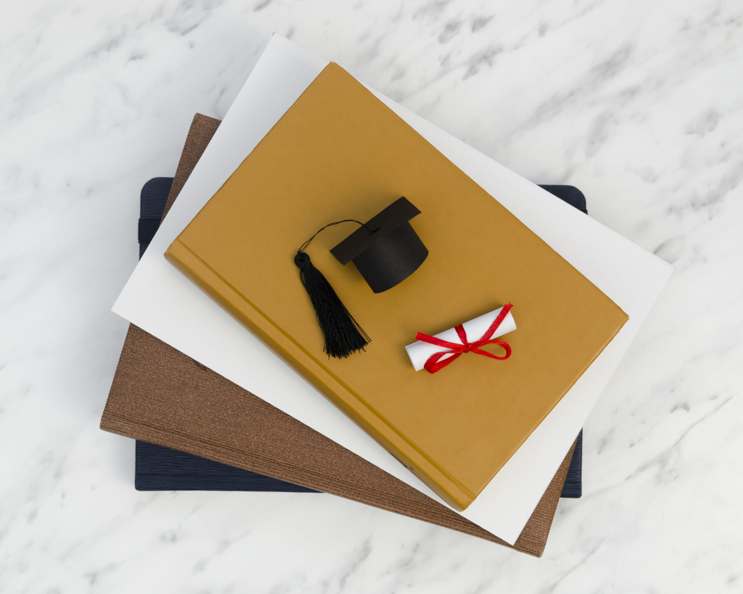 Graduation cap and diploma placed on academic documents