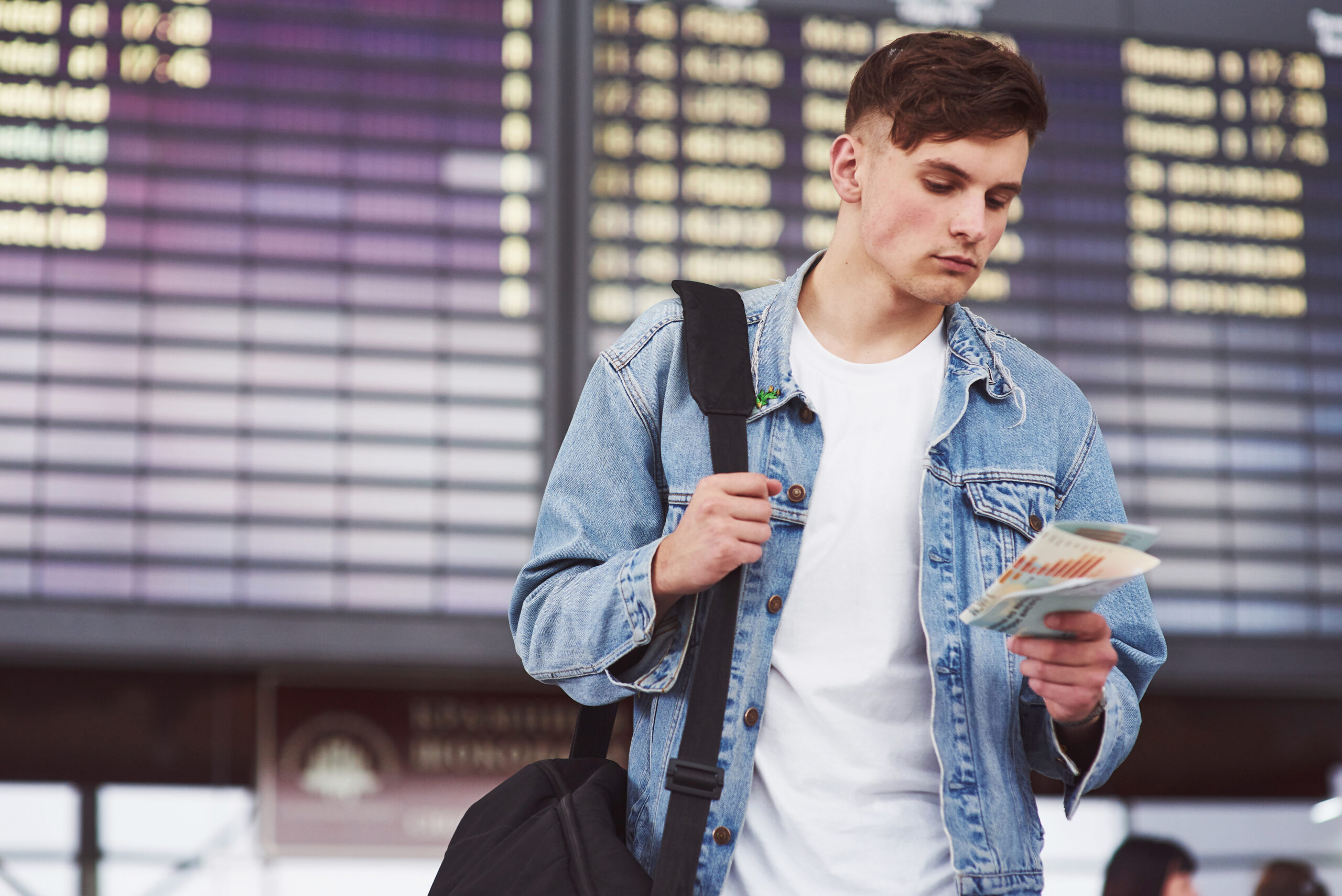 International student with a backpack checking travel documents at an airport