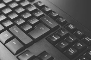 Close-up black computer keyboard with Enter, Shift, Backspace, Delete, and navigation keys visible.